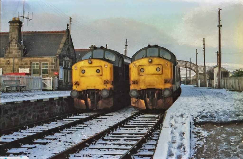 Two yellow trains at snowy station.